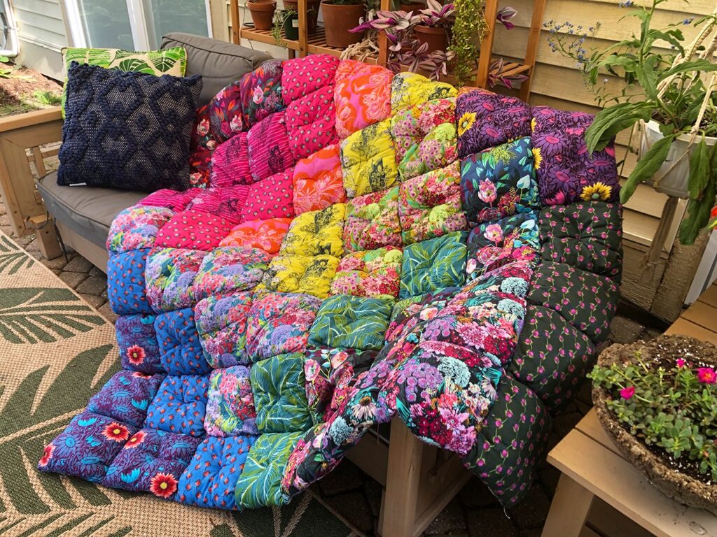 A puffy quilt in bright rainbow colors on outside patio