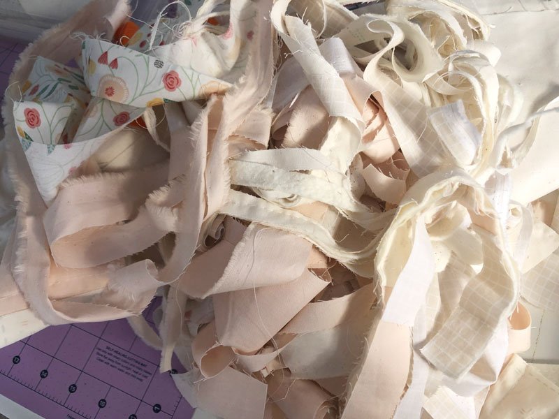 Fabric scraps and strips of muted bieges and creams