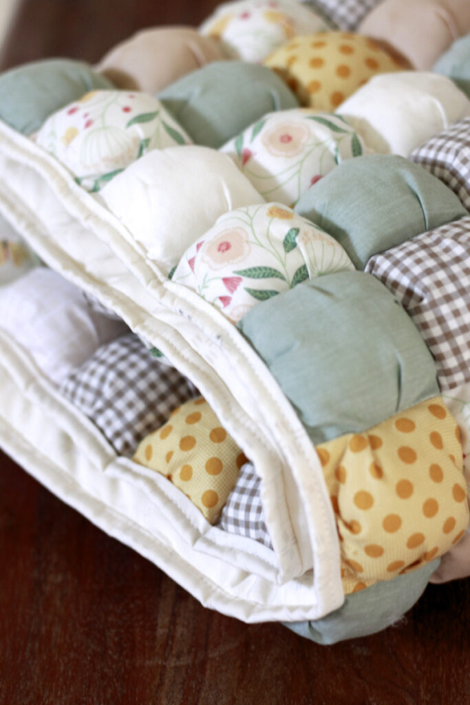 light pastel, winnie the pooh or hundred acre woods color scheme for baby quilt folded on a dark wood table.