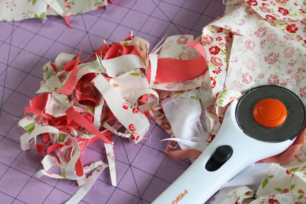 Pink and white floral fabrics with Fiskers rotary cutter on a purple cutting mat. 