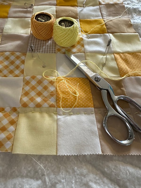 yellow and gold squares, sewing scissors, thread, in progress winnie the pooh quilt