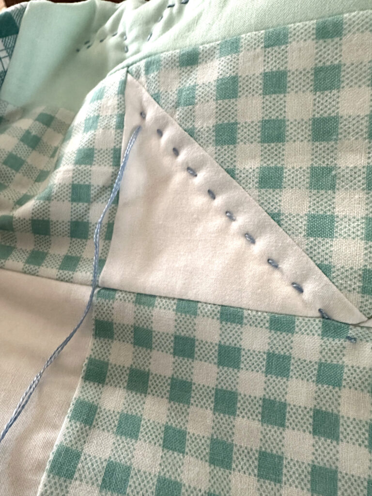 light blue chunky hand quilted stitched on a gingham patterned quilt