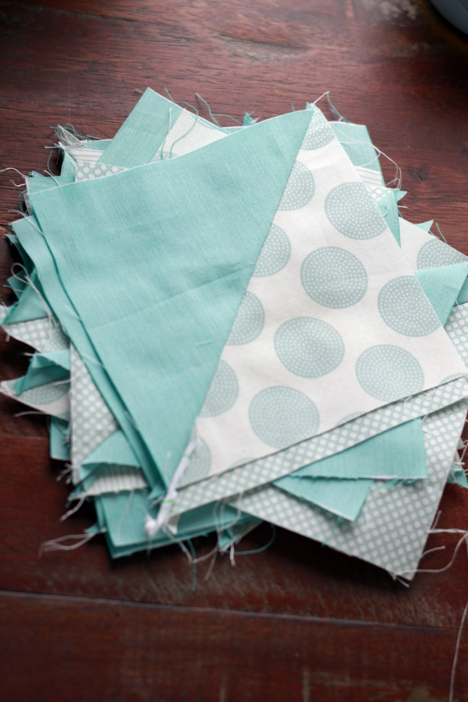 A pile of half teal half cream and teal prints of half-triangle squares.